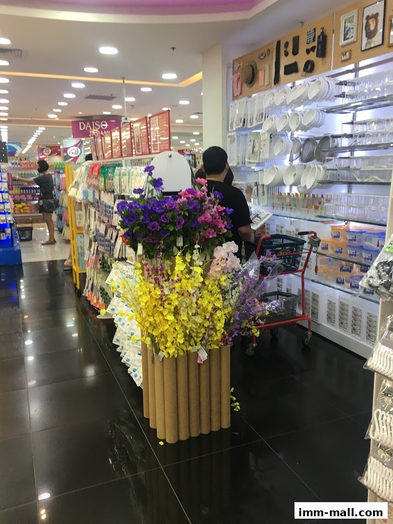 Interior view of a Daiso store showcasing aisles of products and decorative floral arrangements.