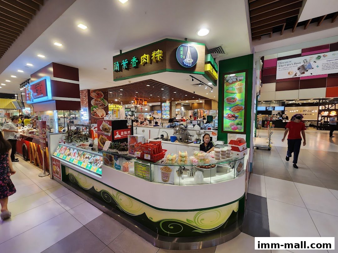 A food stall in a mall selling dumplings and other snacks, with a display of food items and staff serving customers.