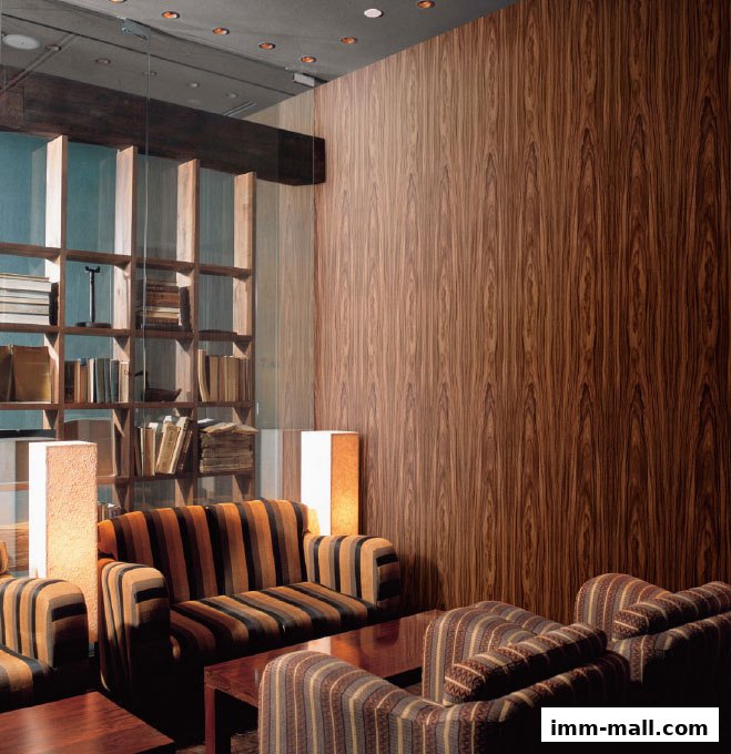 A cozy lounge area with striped sofas, wooden shelves filled with books, and warm lighting.