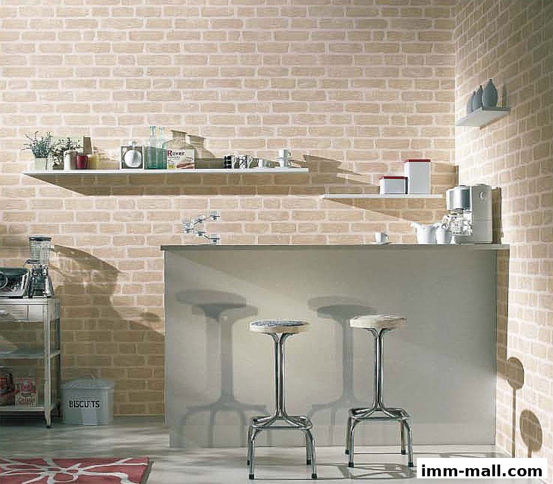 A modern kitchen counter with stools against a brick-patterned wall.