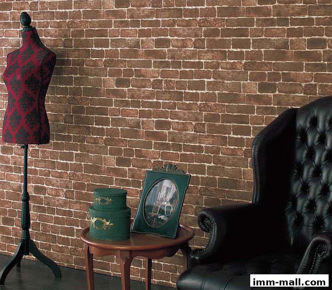 A mannequin with a patterned fabric stands next to a tufted armchair against a brick wall.