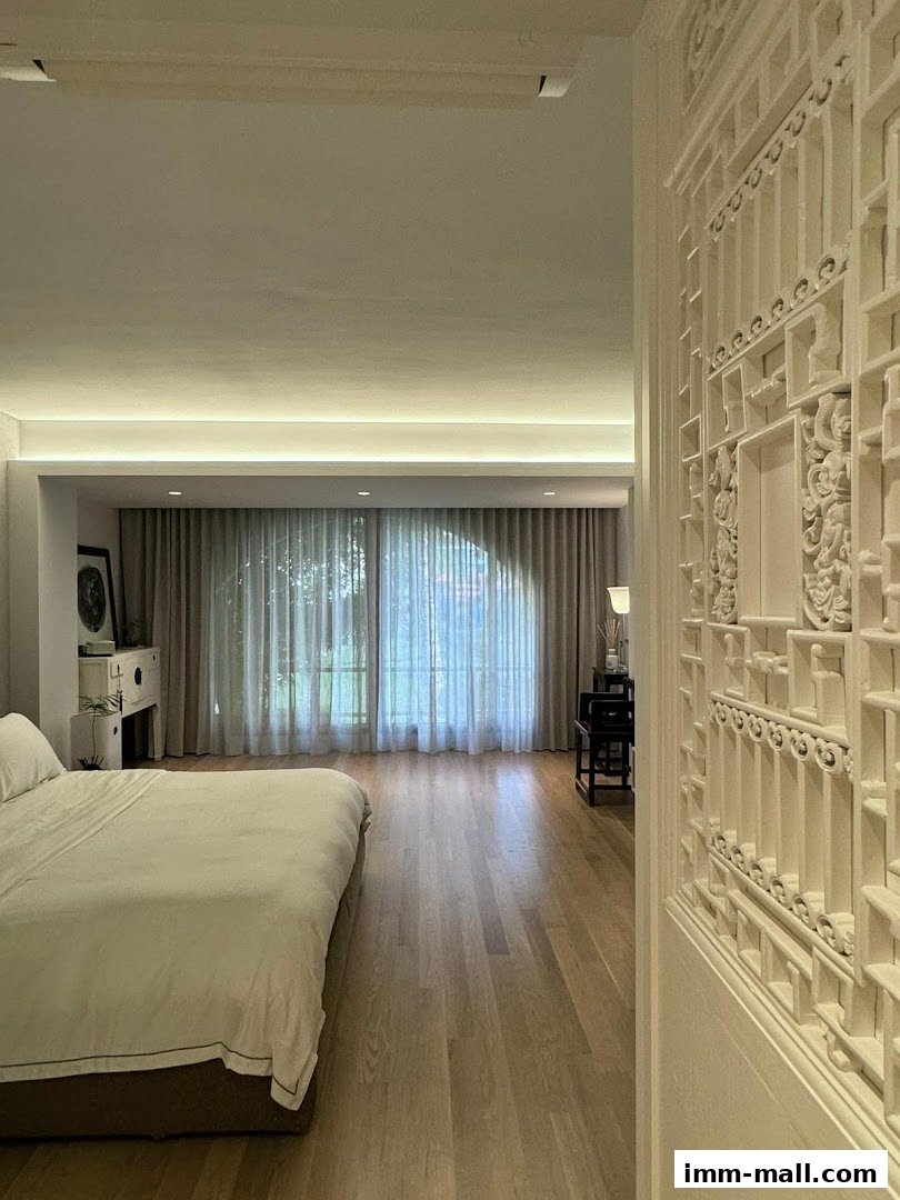 A bedroom interior with a large bed, wooden floors, and decorative wall paneling.