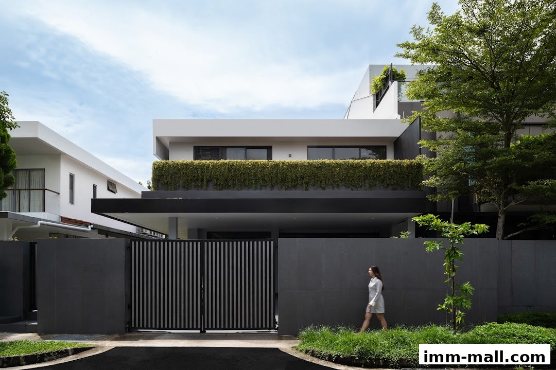 Modern house with a lush green balcony and a woman walking past a dark fence.