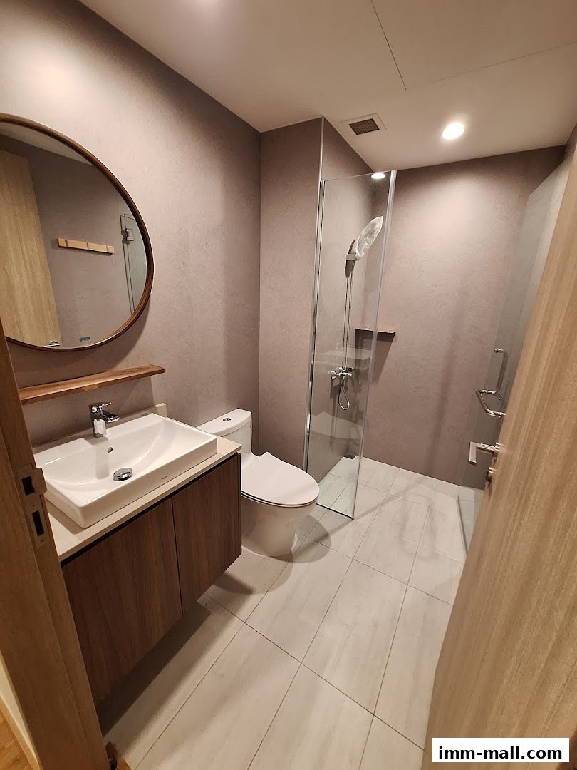 A modern bathroom with a vanity, toilet, and glass-enclosed shower.
