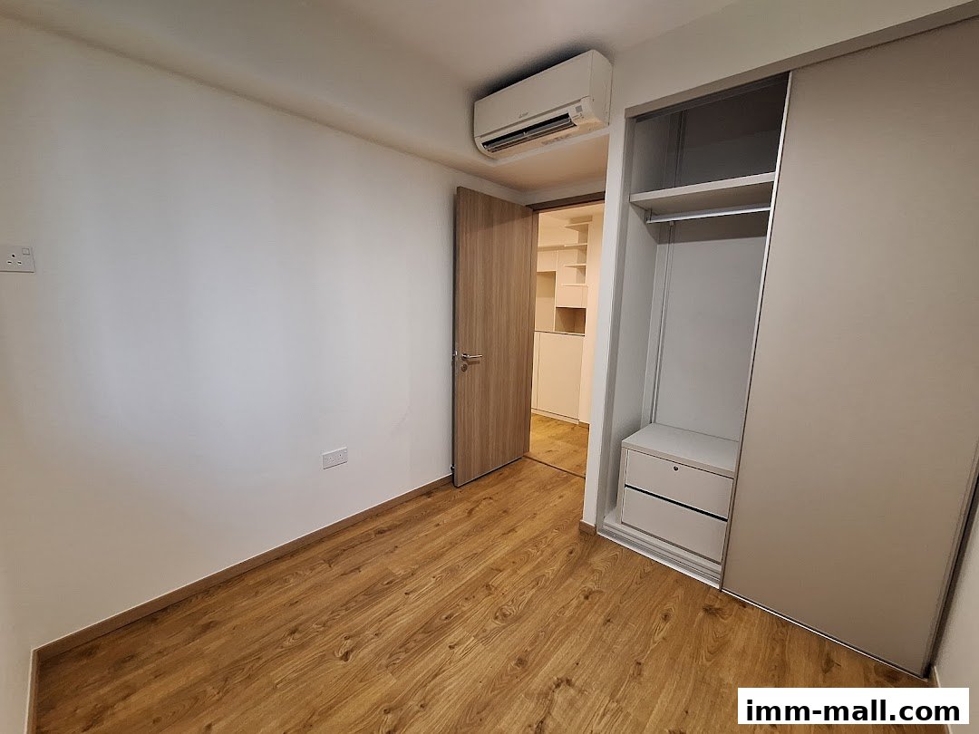 A modern bedroom interior with a built-in wardrobe and an open doorway revealing more storage.