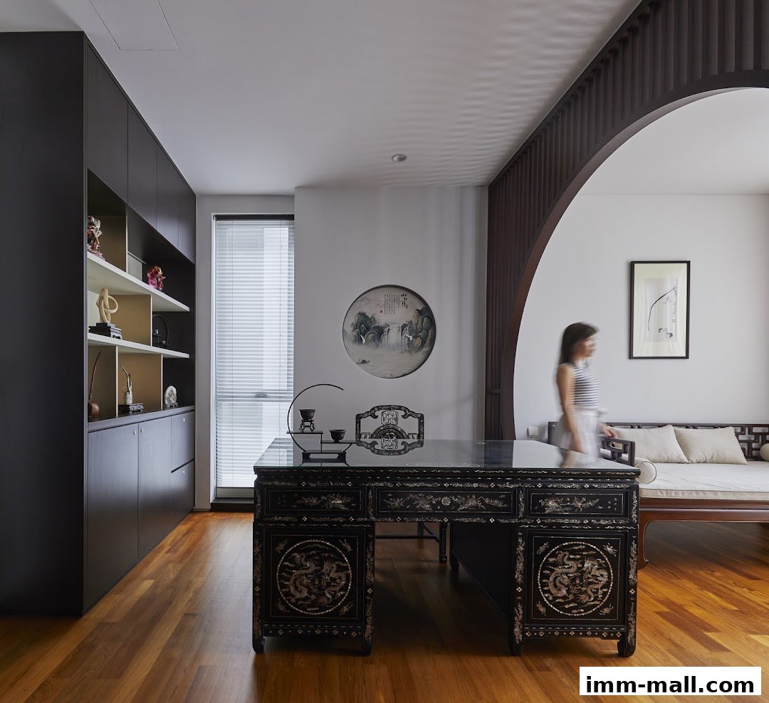 A beautifully designed room with a traditional desk, ornate chair, and a woman walking past.