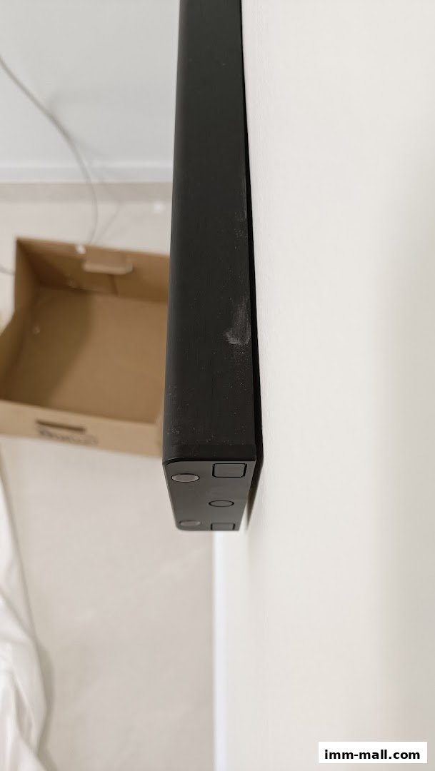 A close-up of a black Eubiq power track mounted on a white wall with a cardboard box in the background.
