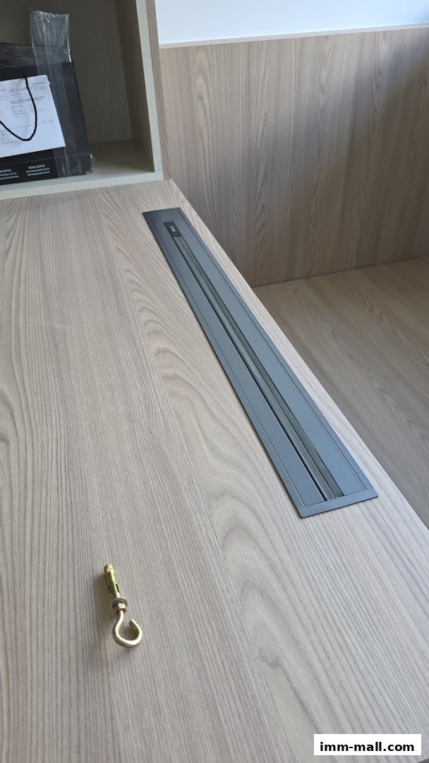 A close-up of a wooden surface with a metal power outlet and a hook.
