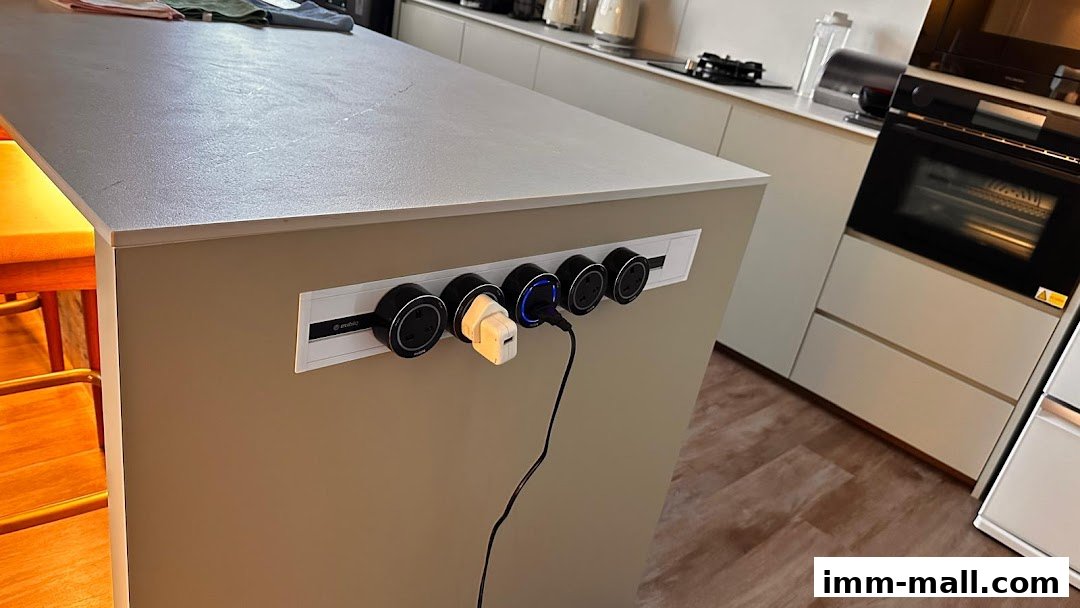 A modern kitchen island with integrated power outlets and charging devices.