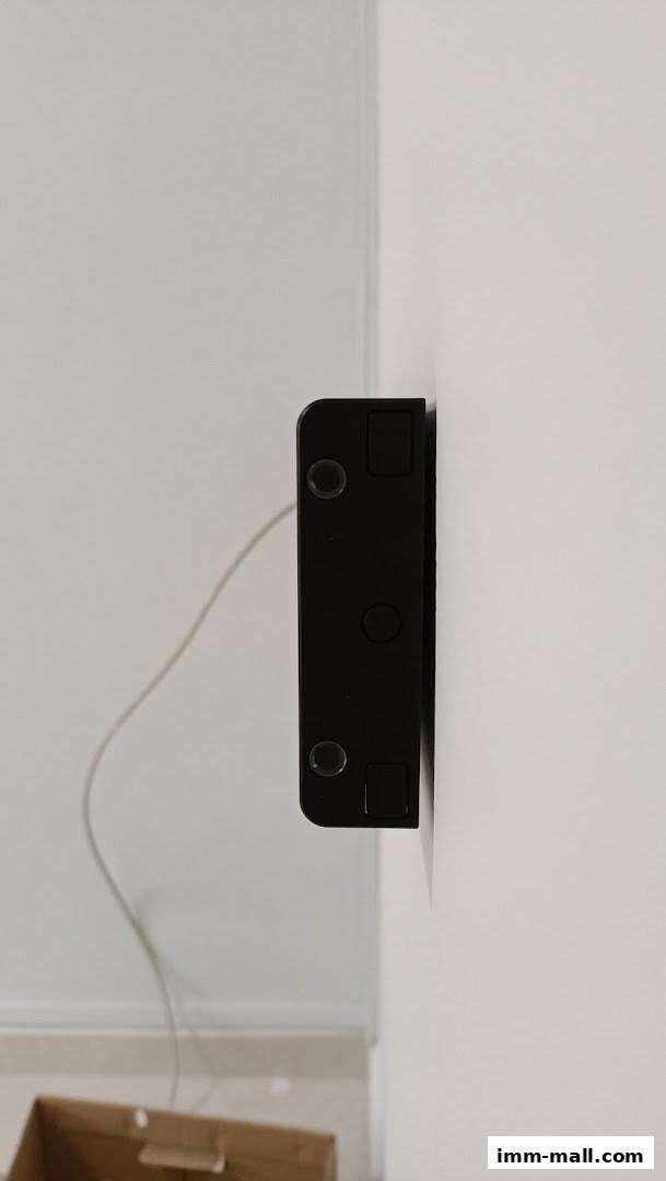 A black Eubiq power track mounted on a white wall with a cable.