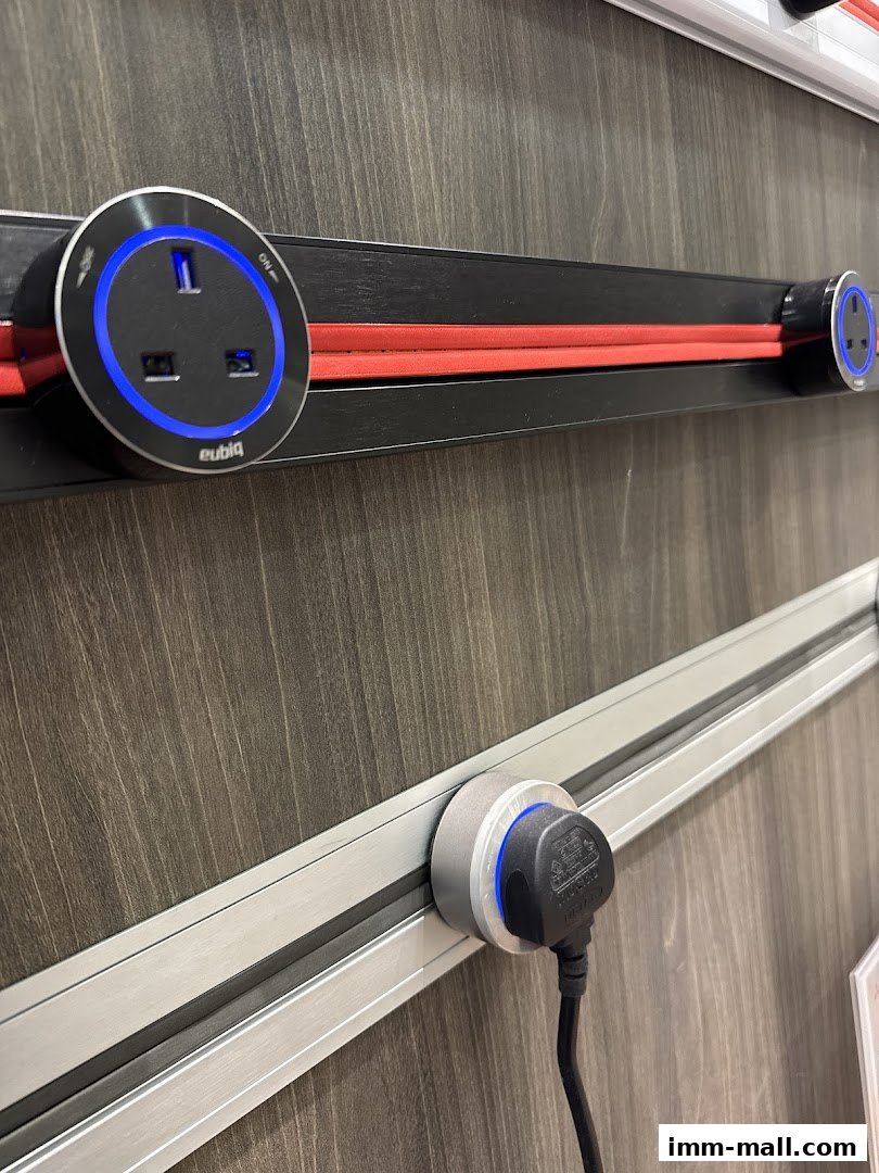 Close-up of Eubiq power track system with illuminated sockets and a plug.