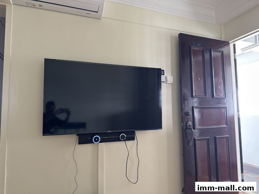 A flat-screen TV is mounted on a wall next to an open wooden door.