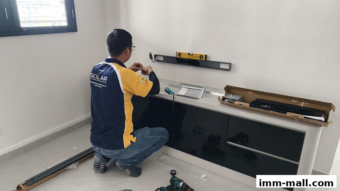 A technician installs a wall mount with a level, using tools and parts from a box.