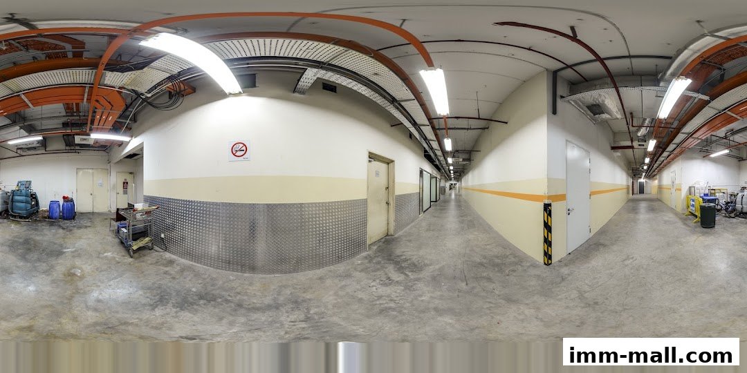 A long, well-lit corridor with doors on either side and exposed ceiling utilities.