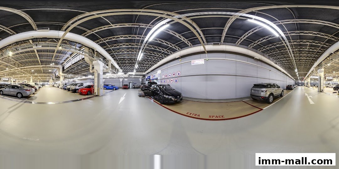 A panoramic view of a spacious, well-lit indoor parking facility with multiple cars parked.