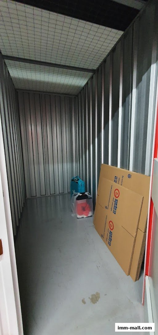 Interior of an empty storage unit with some boxes and bags inside.