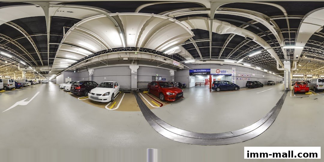 A panoramic view of a well-lit indoor parking garage with several cars parked.
