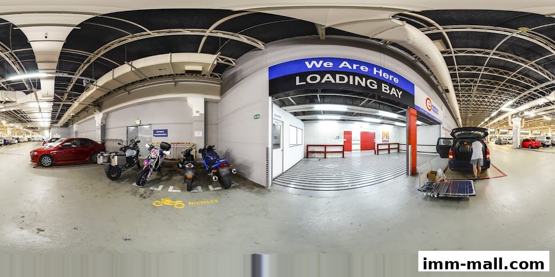 Loading bay area with cars, motorcycles, and people unloading items from a car.