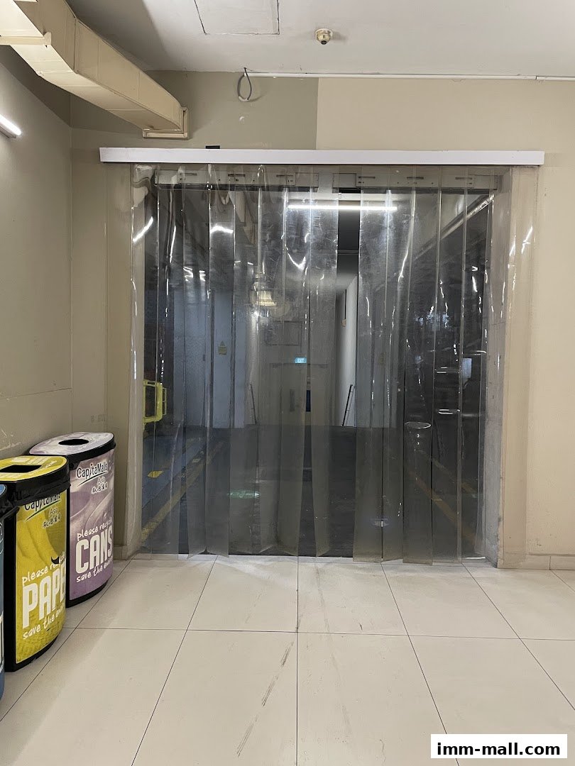 Entrance to Extra Space IMM with clear plastic strip curtains and recycling bins.