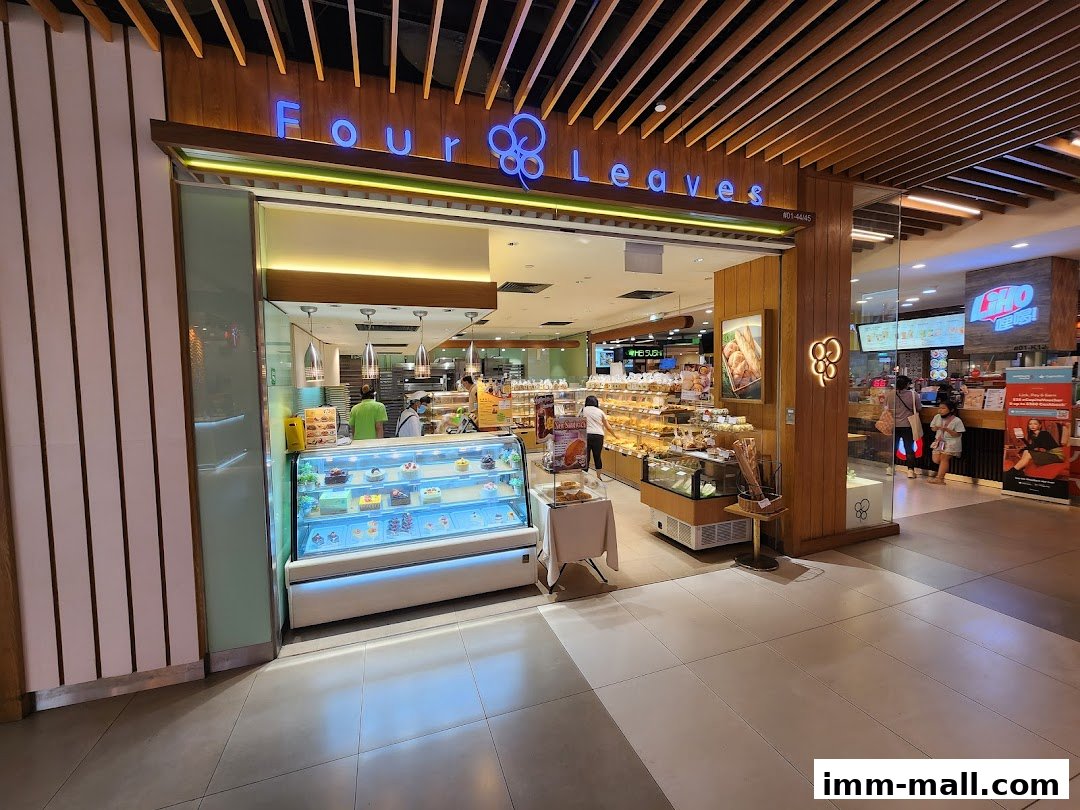 The entrance of a bakery shop called Four Leaves, showcasing cakes and bread.
