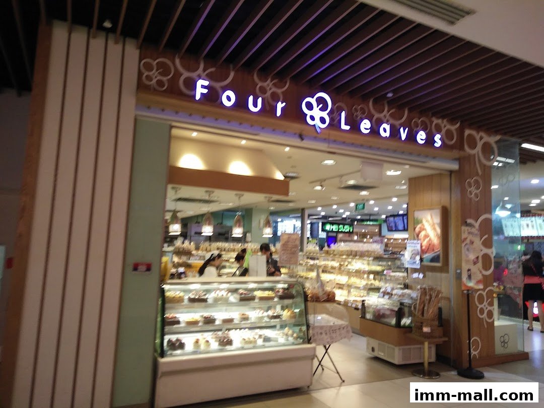 The exterior of a bakery shop named Four Leaves, showcasing display cases filled with pastries and cakes.