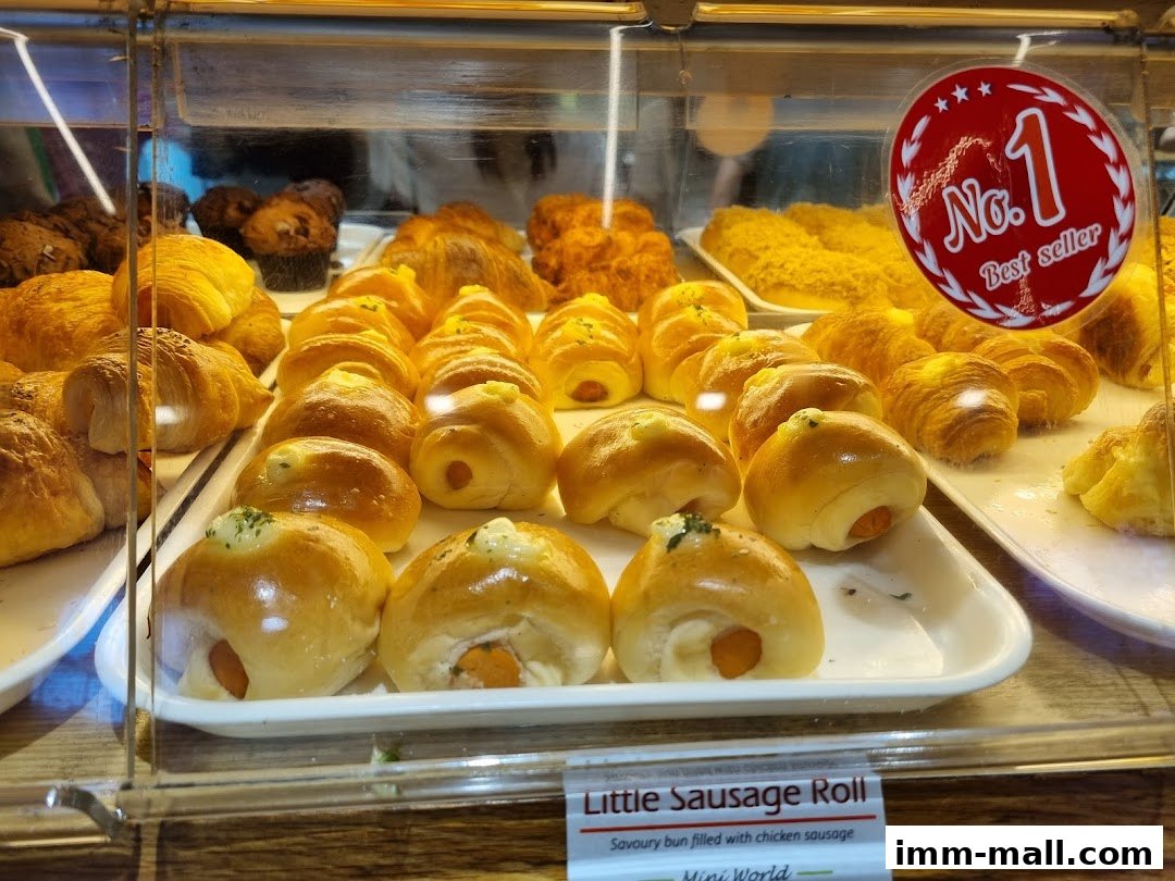 A display case filled with various freshly baked pastries and buns, including croissants and sausage rolls.