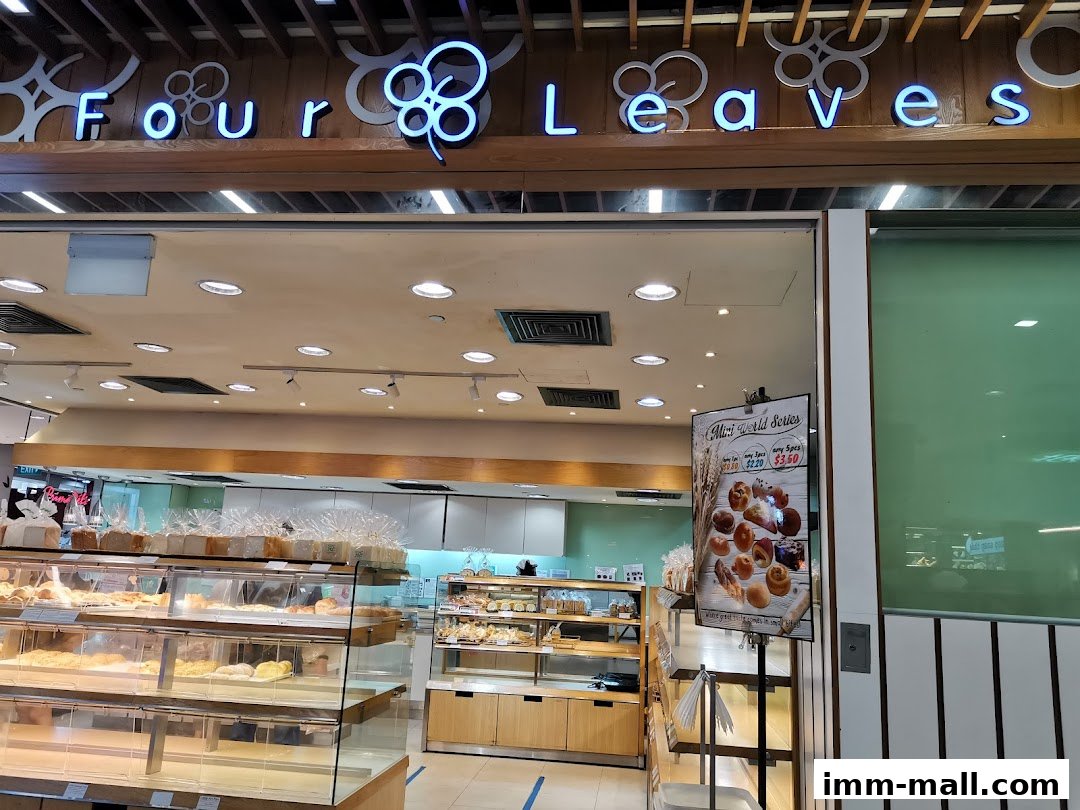 The entrance of a bakery shop named Four Leaves, showcasing display shelves filled with bread and pastries.