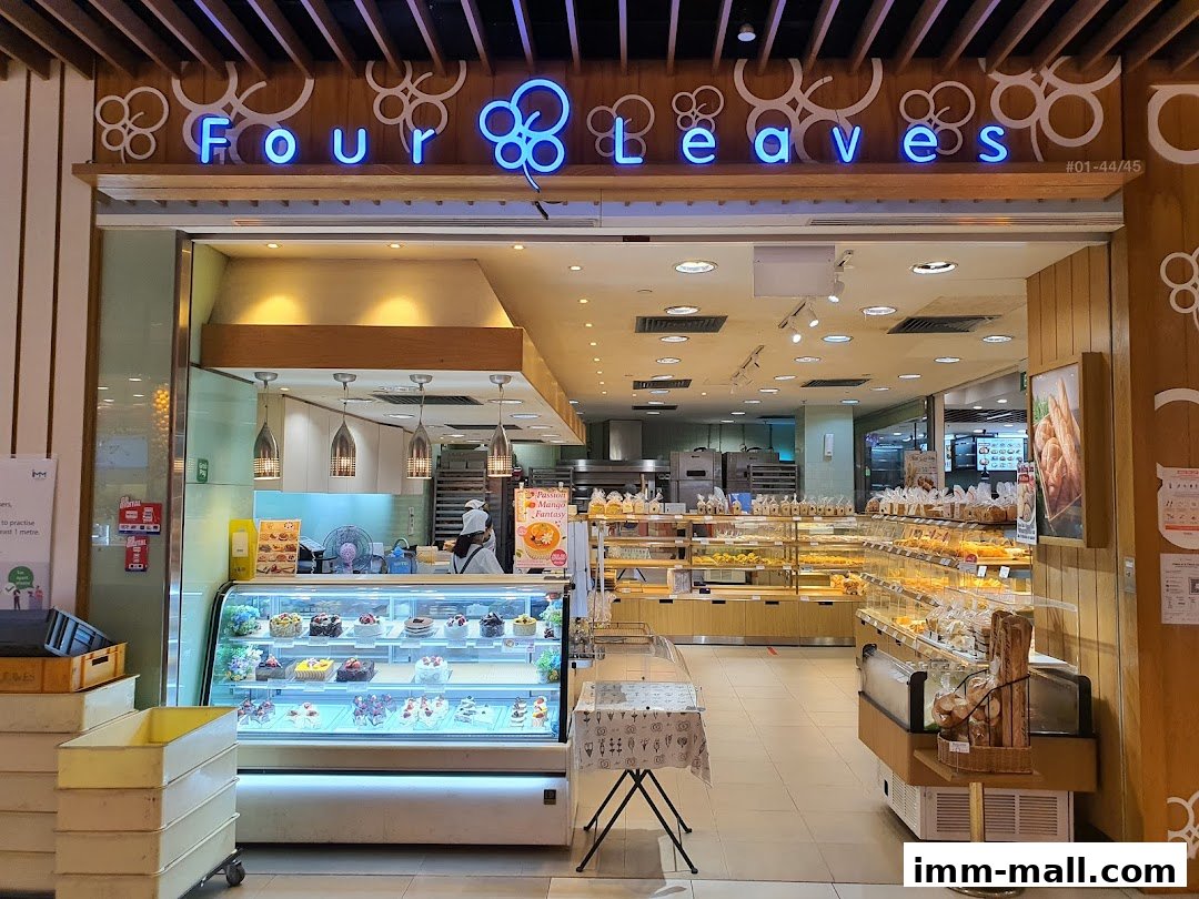 The exterior of a bakery shop called Four Leaves, showcasing cakes and bread.
