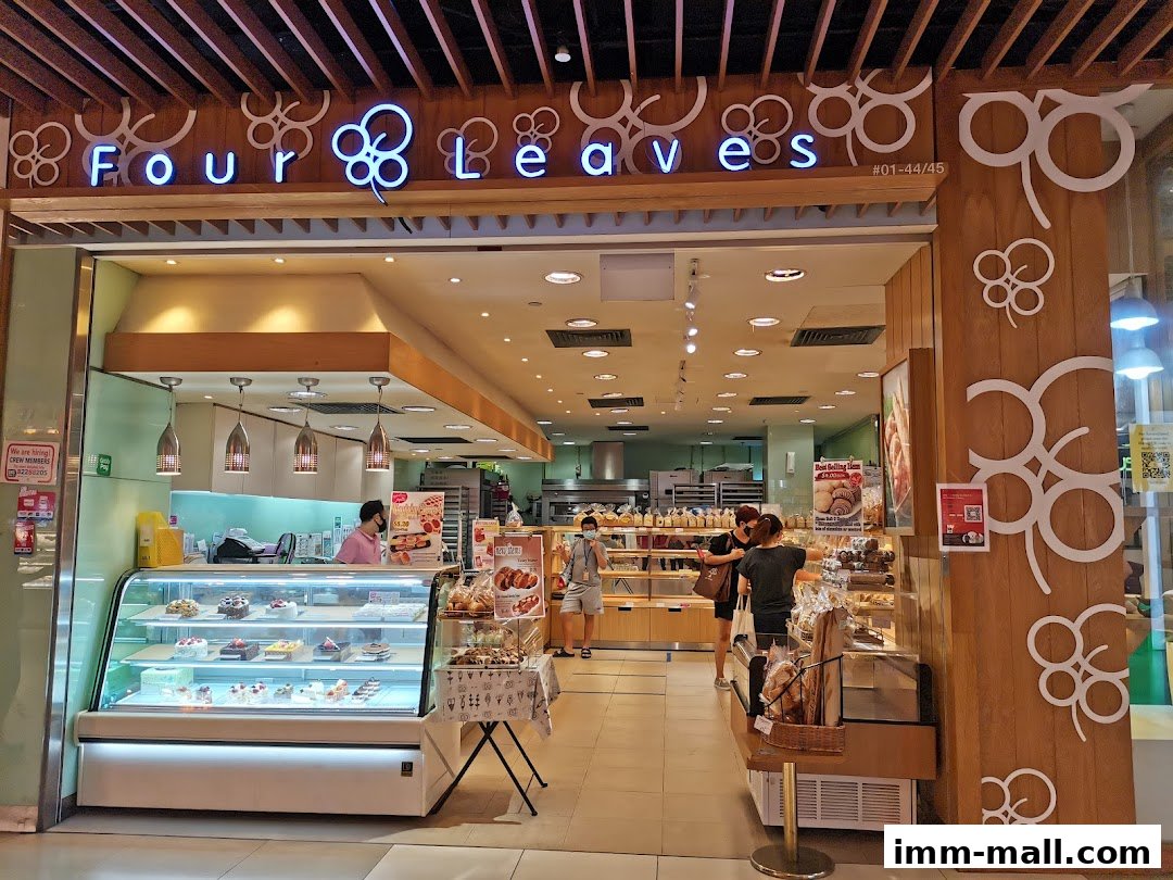 The entrance of a bakery shop called Four Leaves, showcasing cakes and bread.