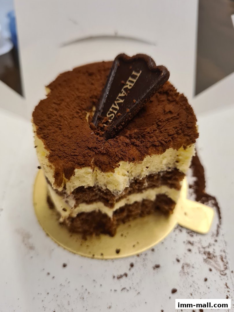 A delicious tiramisu cake with cocoa powder and a chocolate garnish.