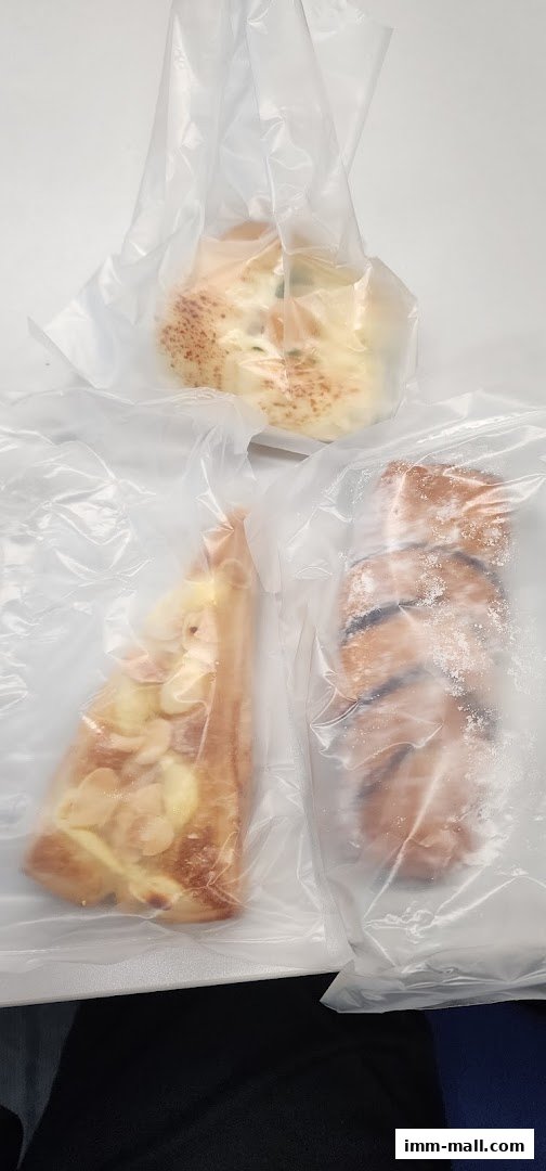 Three freshly baked pastries are individually wrapped in clear plastic bags.