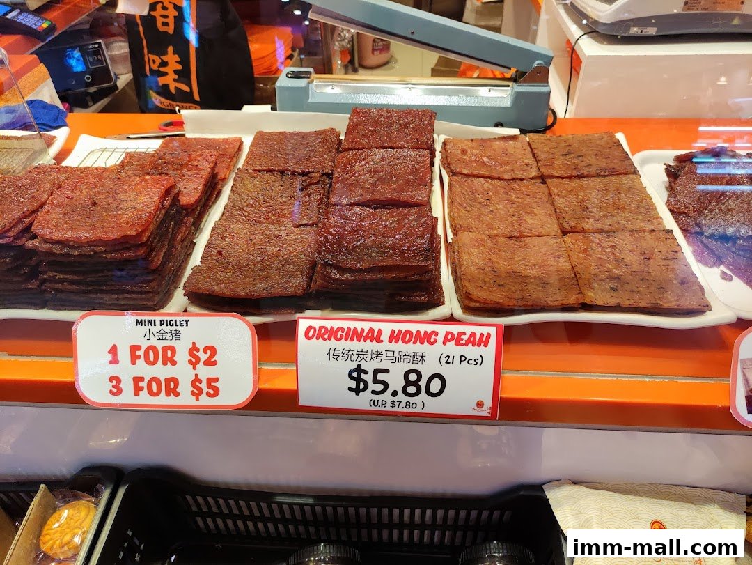 A display of freshly made bak kwa (dried meat) with price tags and promotional offers.
