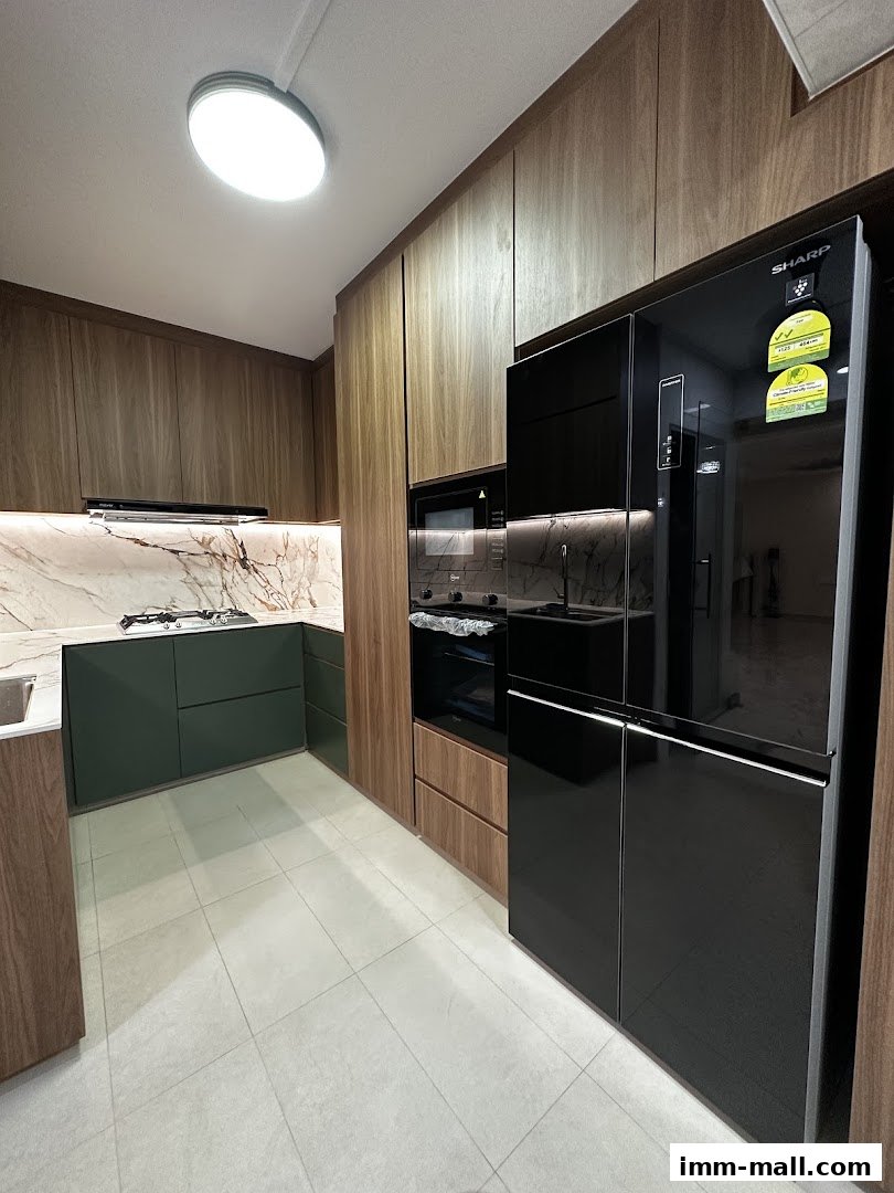 A modern kitchen with dark green cabinets, marble backsplash, and a sleek black refrigerator.