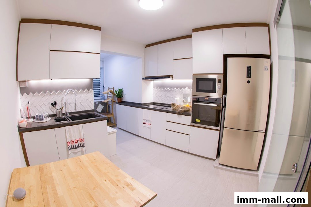 A modern, white kitchen with a wooden table and a cat lounging on the counter.