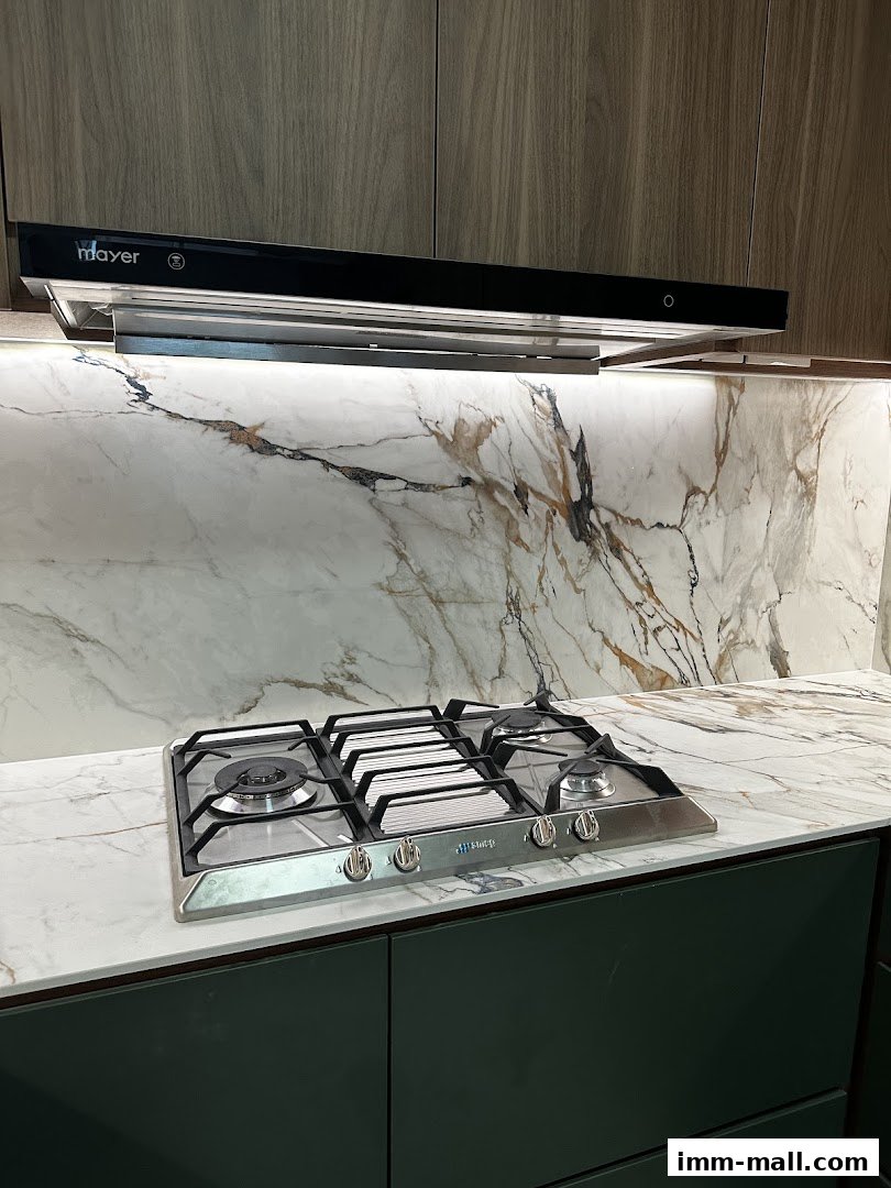 A modern kitchen countertop featuring a gas stove, marble backsplash, and sleek cabinetry.