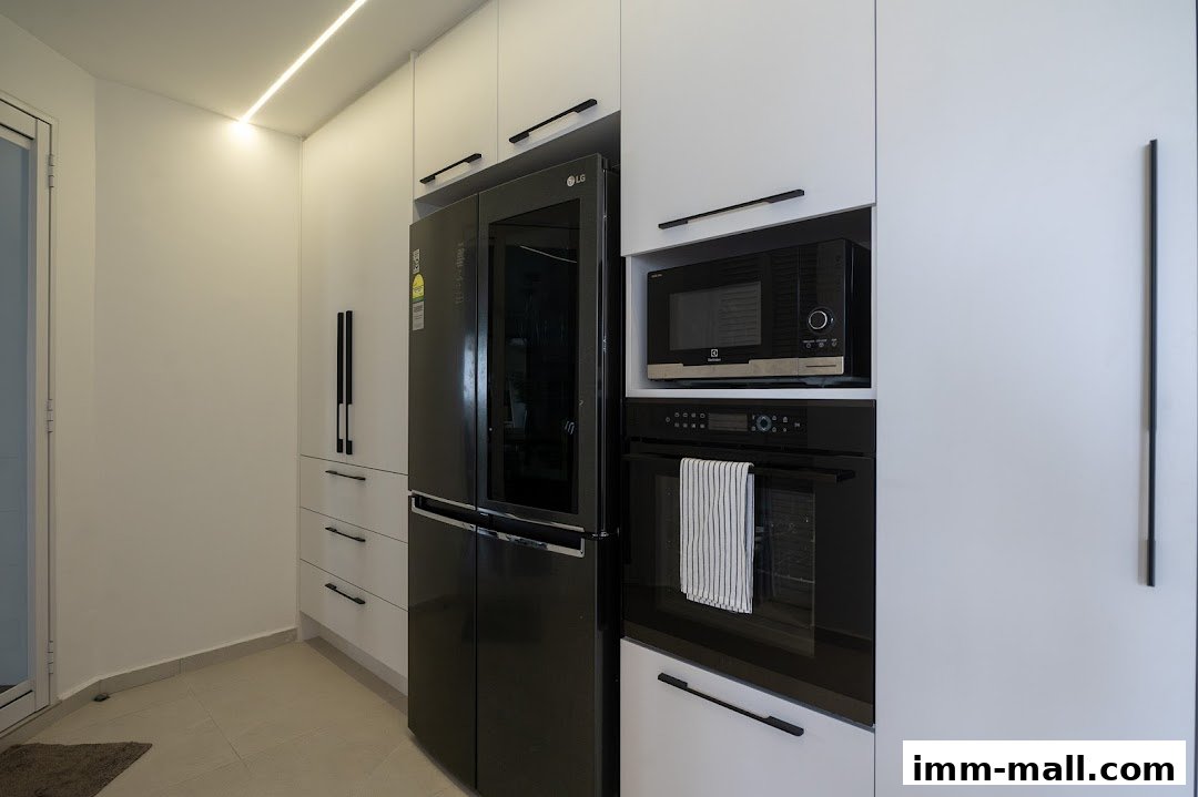 Modern kitchen with sleek white cabinets, a black LG refrigerator, and built-in Electrolux appliances.
