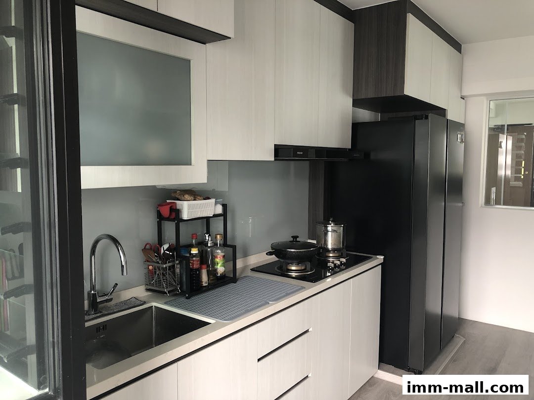 A modern kitchen with white and grey cabinets, a black refrigerator, and a sink area.
