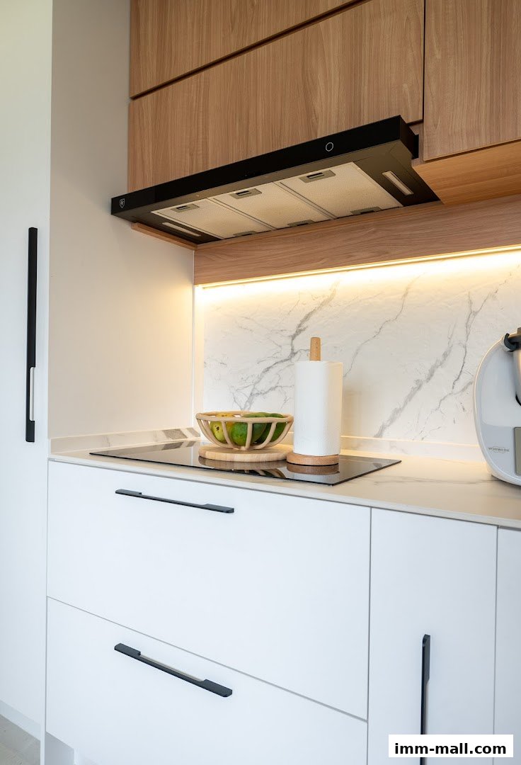 A modern kitchen counter with white cabinets, a marble backsplash, and wooden accents.