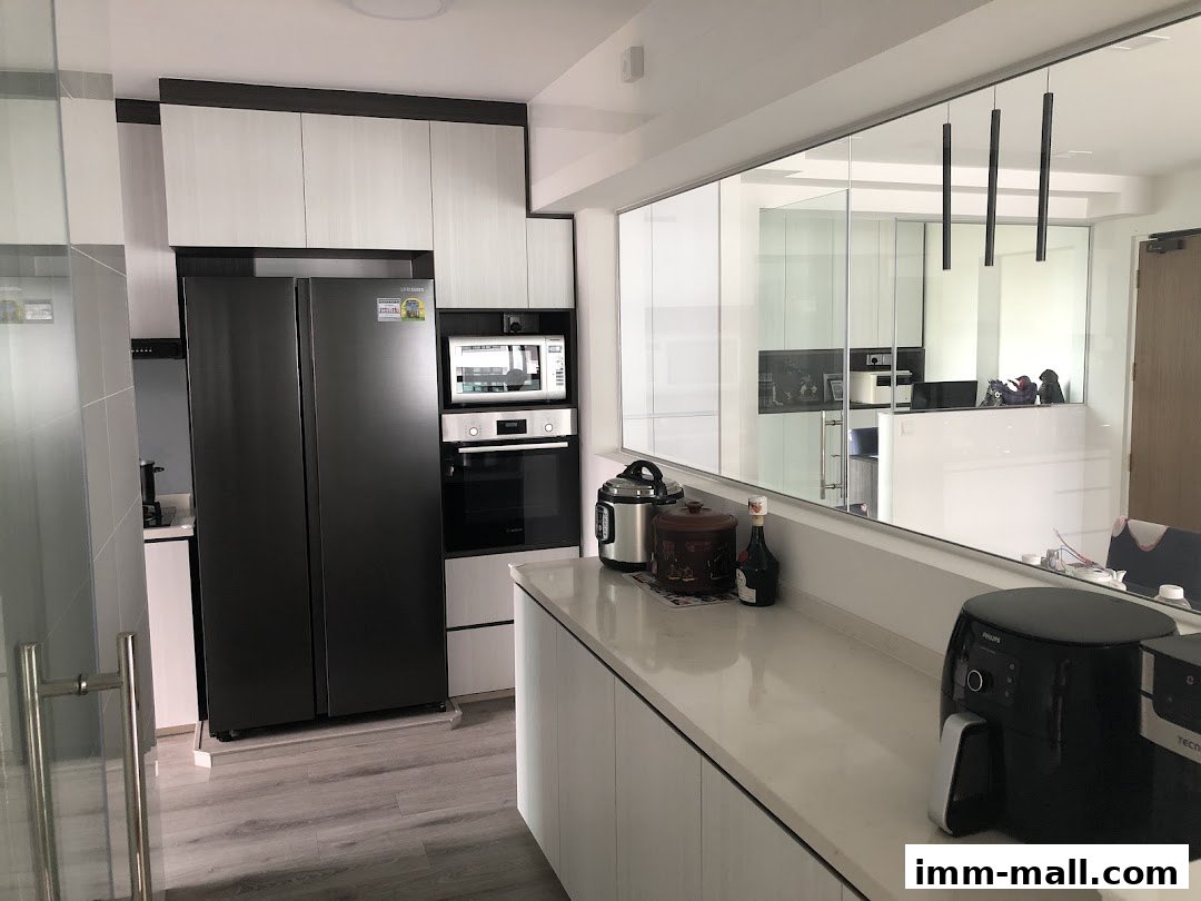 A modern kitchen with sleek cabinetry, a large refrigerator, and various appliances on the countertop.