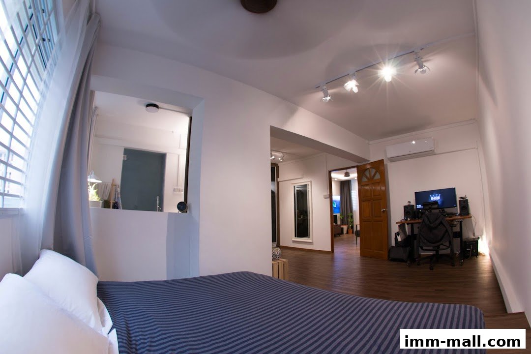 Interior view of a modern living space with a bed, desk, and open doorways.