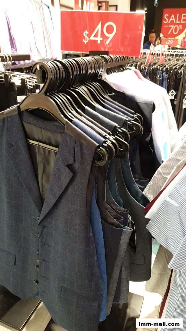 A rack of men's vests and shirts on display with sale signs.