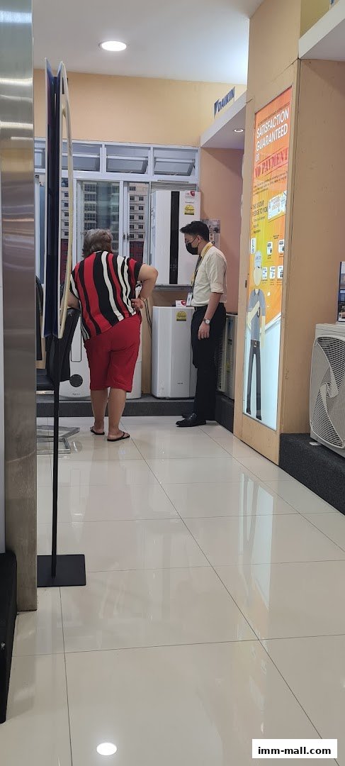 A customer consults with a salesperson in an electronics store, surrounded by air conditioning units.