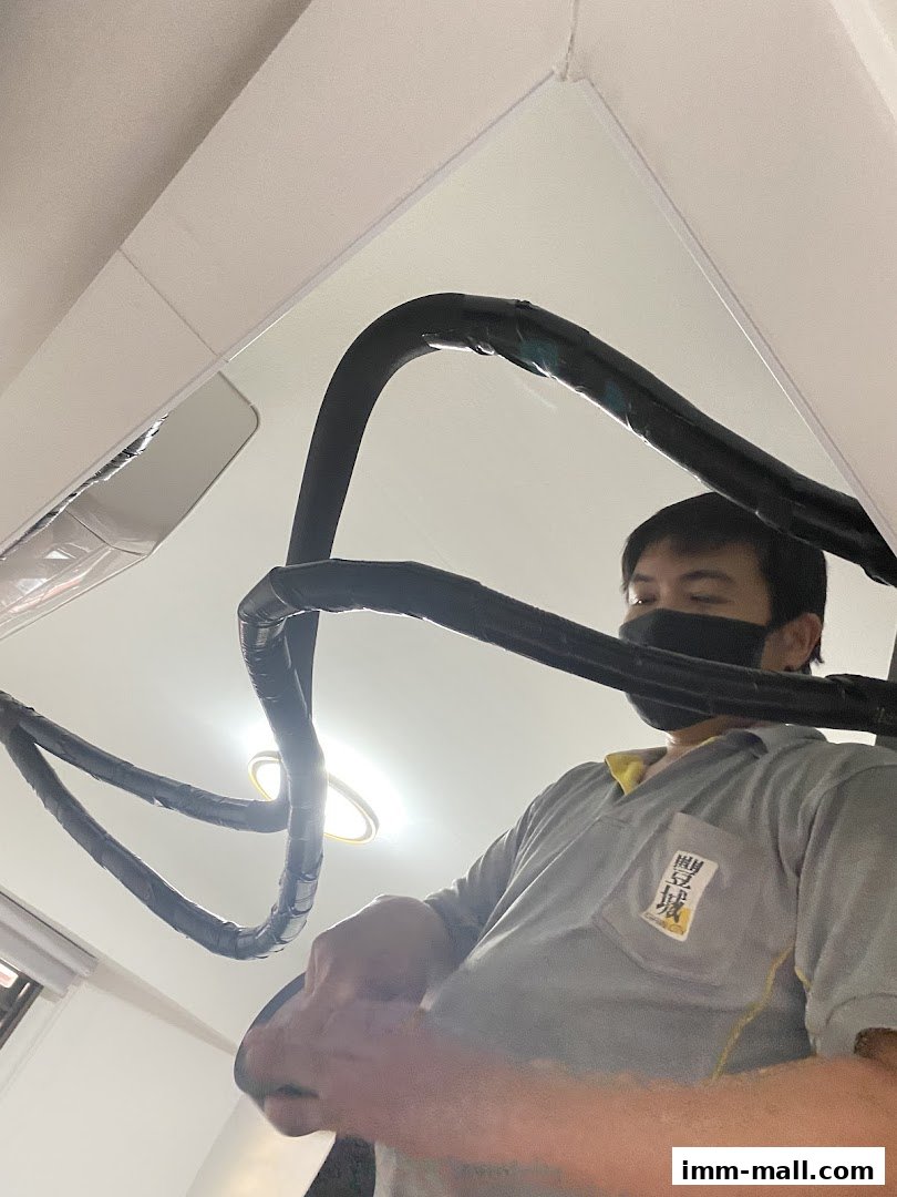 A technician wearing a mask works on air conditioning pipes.