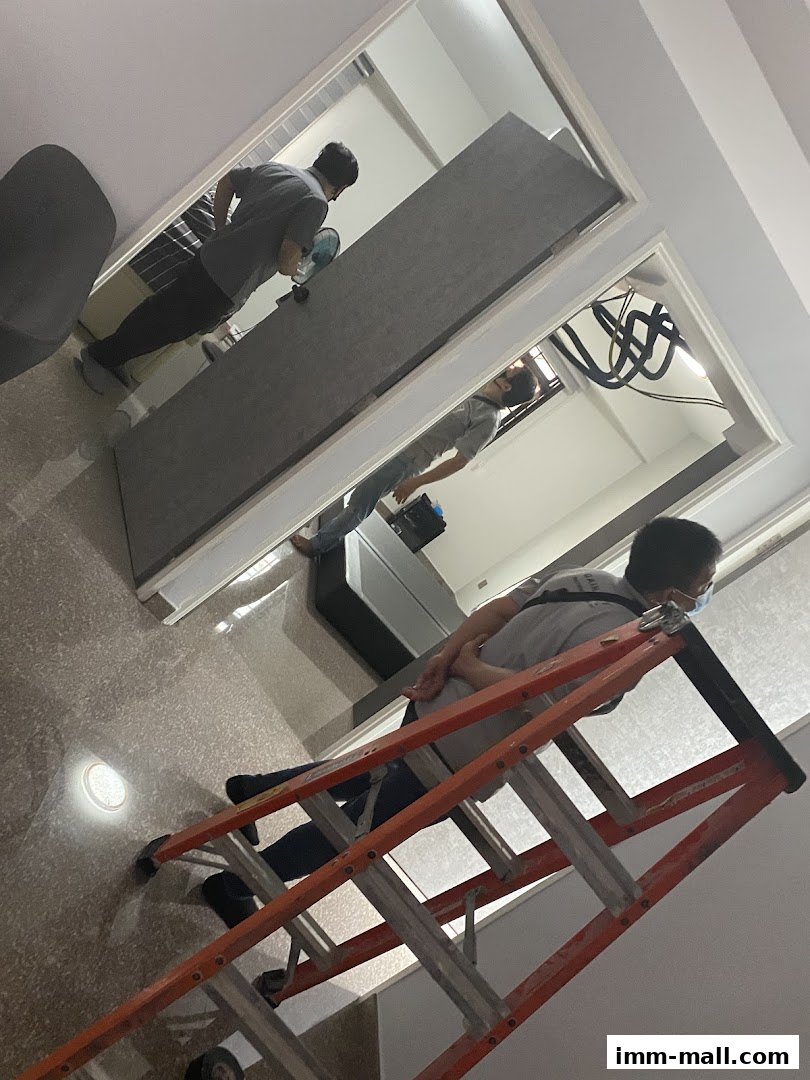 Workers are installing a large panel inside a store, with one on a ladder.