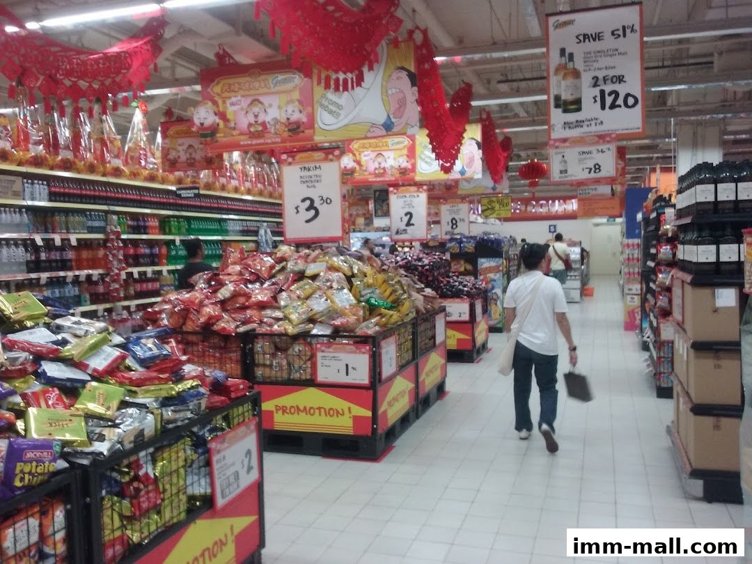 Aisle in a supermarket with promotional displays and shoppers.