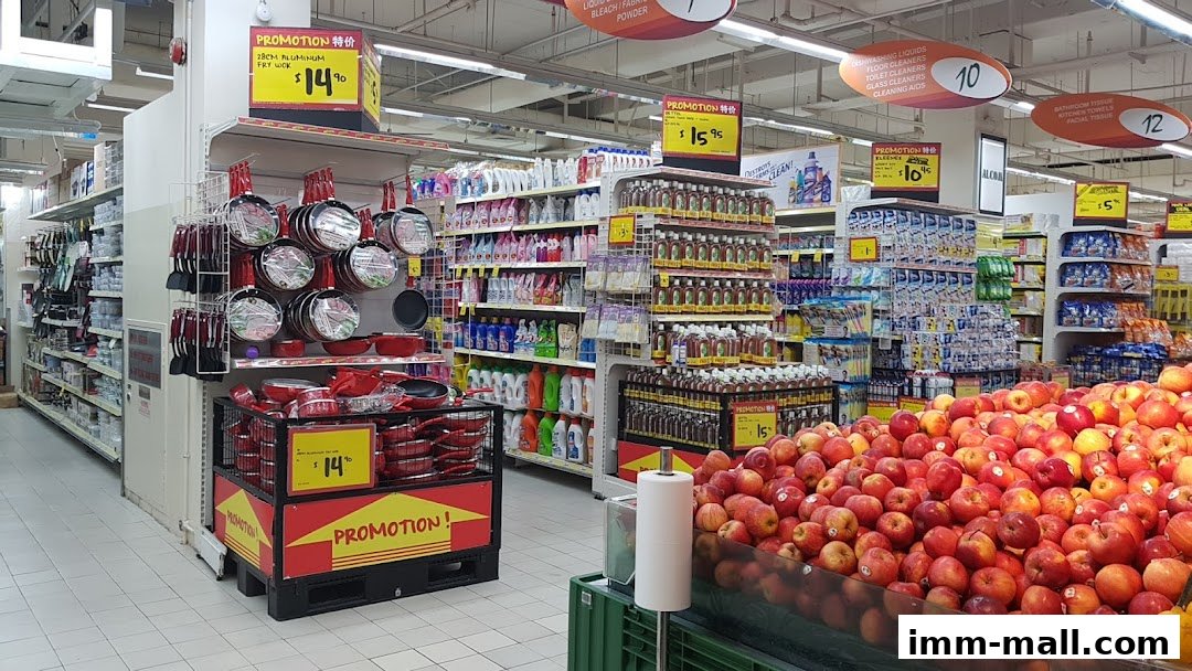 A supermarket aisle displaying cookware, cleaning supplies, and fresh apples with promotional signs.