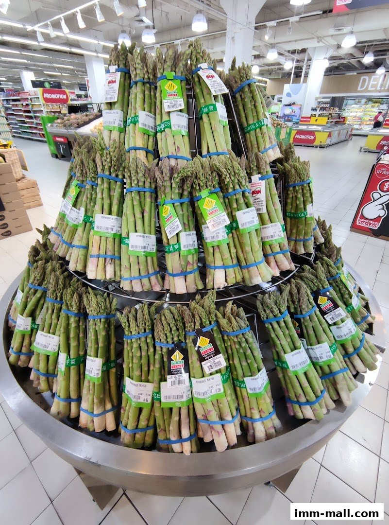 A large display of fresh asparagus bundles in a supermarket.