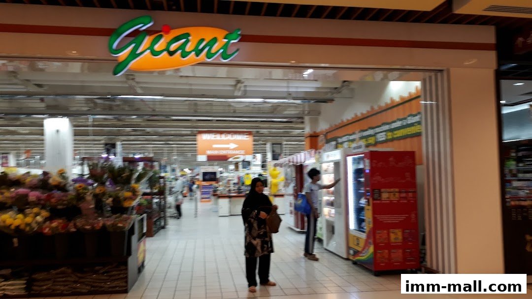 The entrance of Giant Supermarket with a flower display and vending machines.