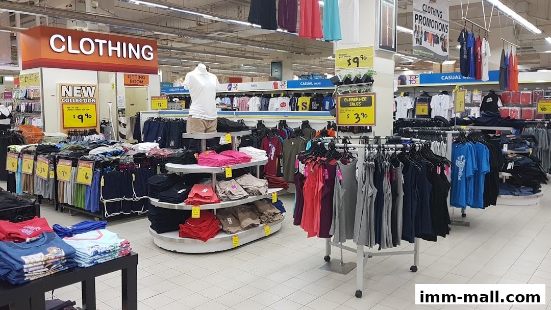 A wide view of a clothing section in a supermarket with various apparel displayed.
