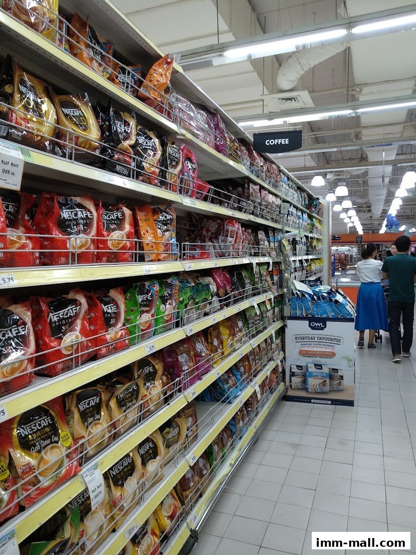 A wide aisle in a supermarket with shelves stocked with coffee products.